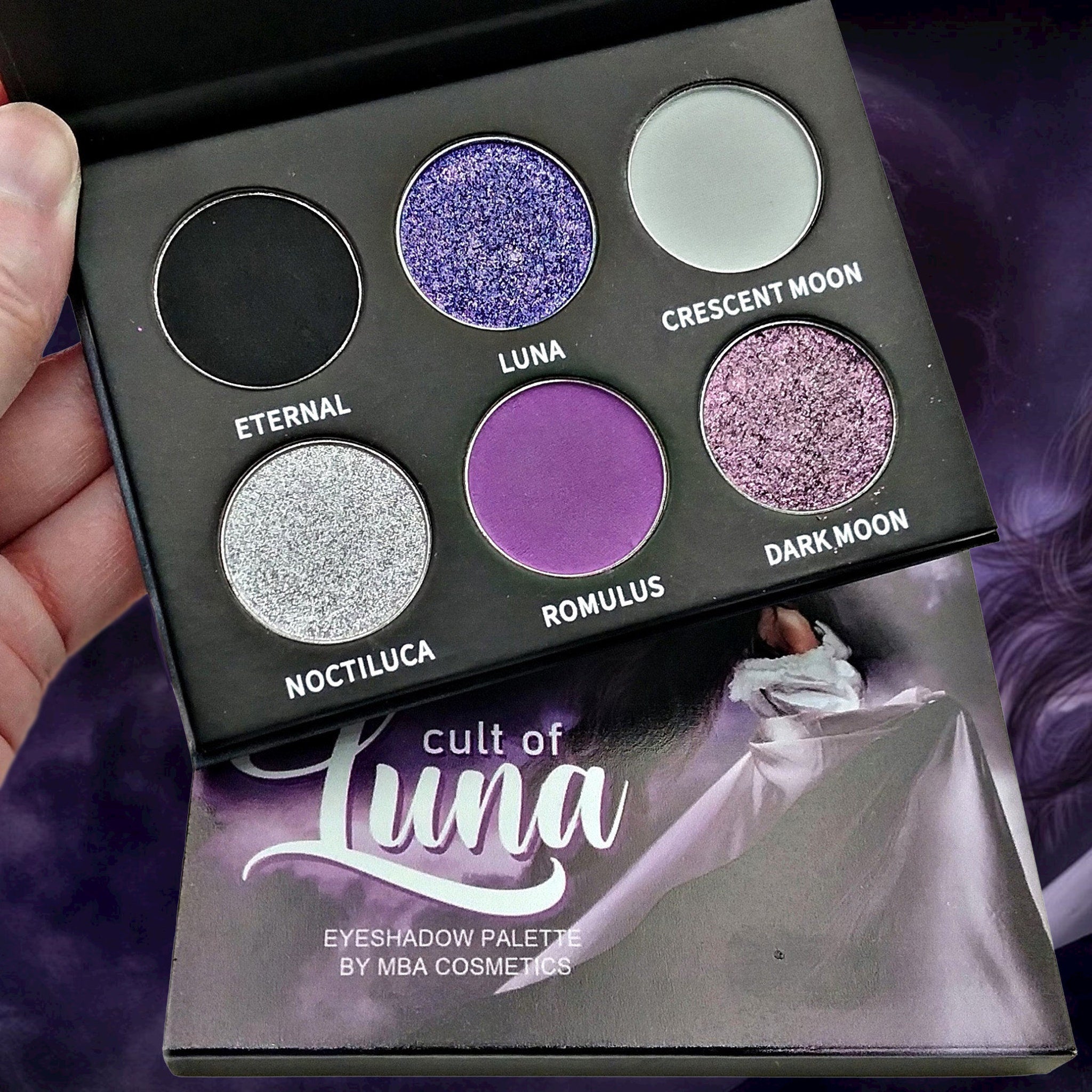 Close-up of a makeup brush applying shimmery taupe eyeshadow from the Luna palette onto eyelid