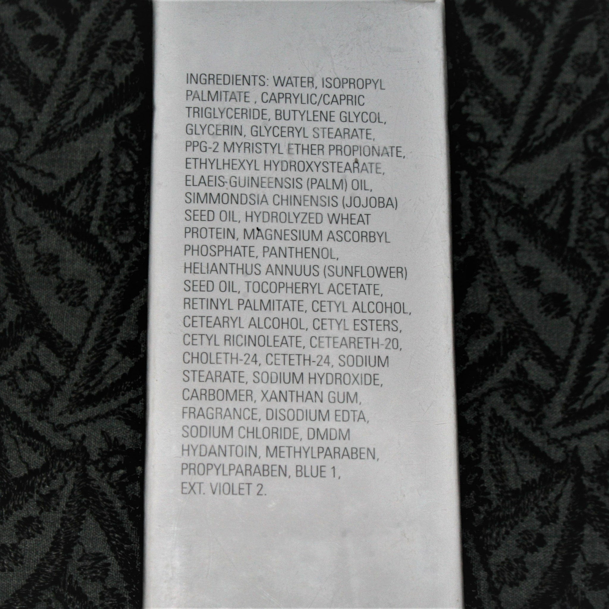 Ingredients list on white paper with black floral pattern background, text visible