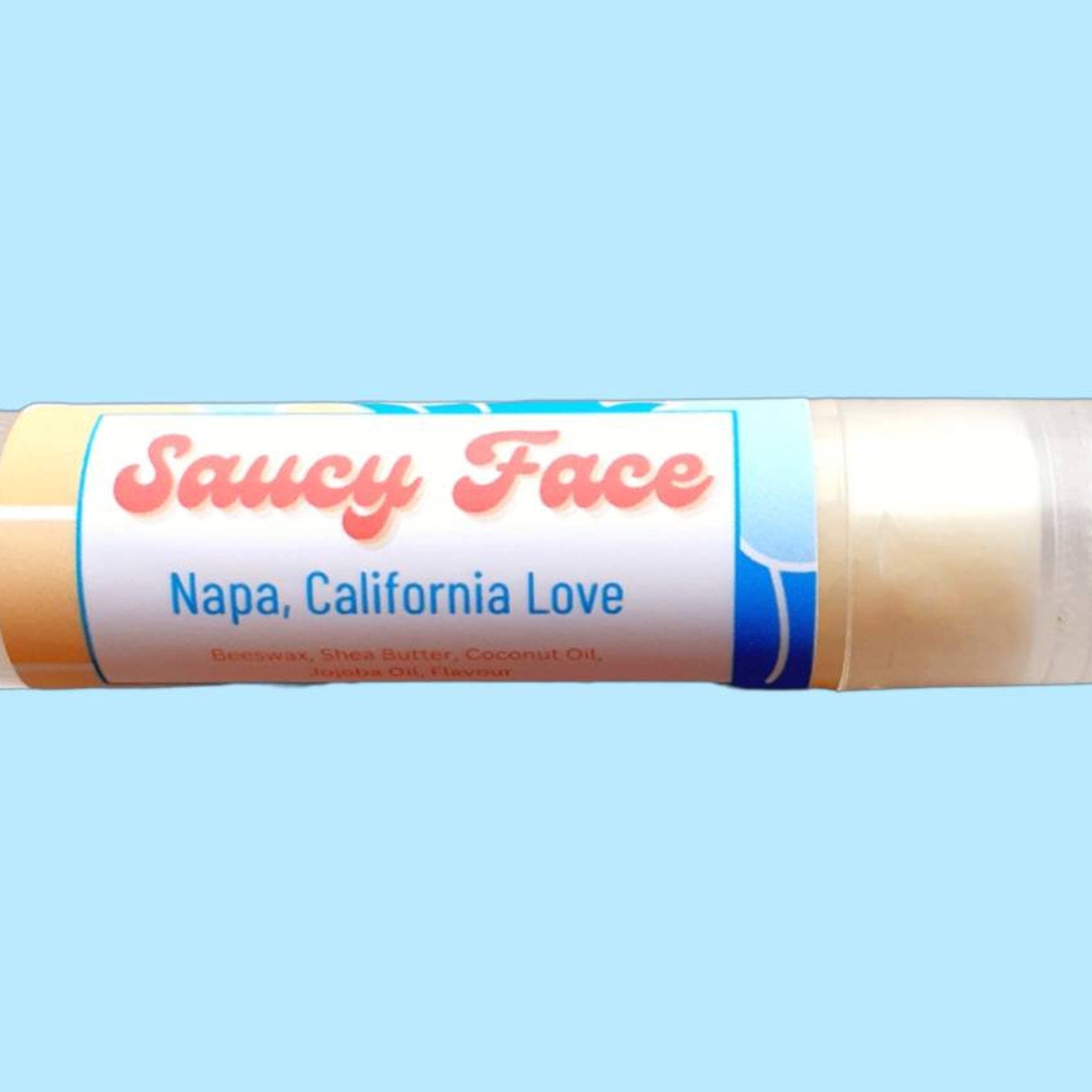 Lip balm tube with "Saucy Face" label, white and blue details, and clear tube