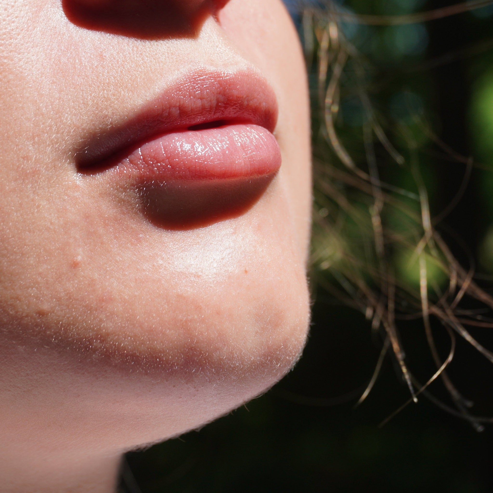 Lip gloss on pink lips with fair skin, close-up view of face detail