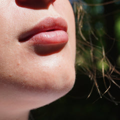 Lip gloss on pink lips with fair skin, close-up view of face detail