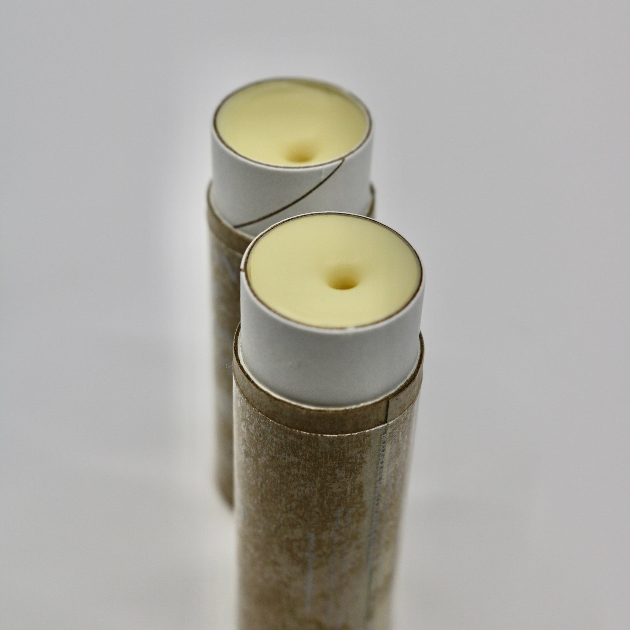 Lip balm tubes with yellow balm, white and brown paper casing, and a cylindrical shape