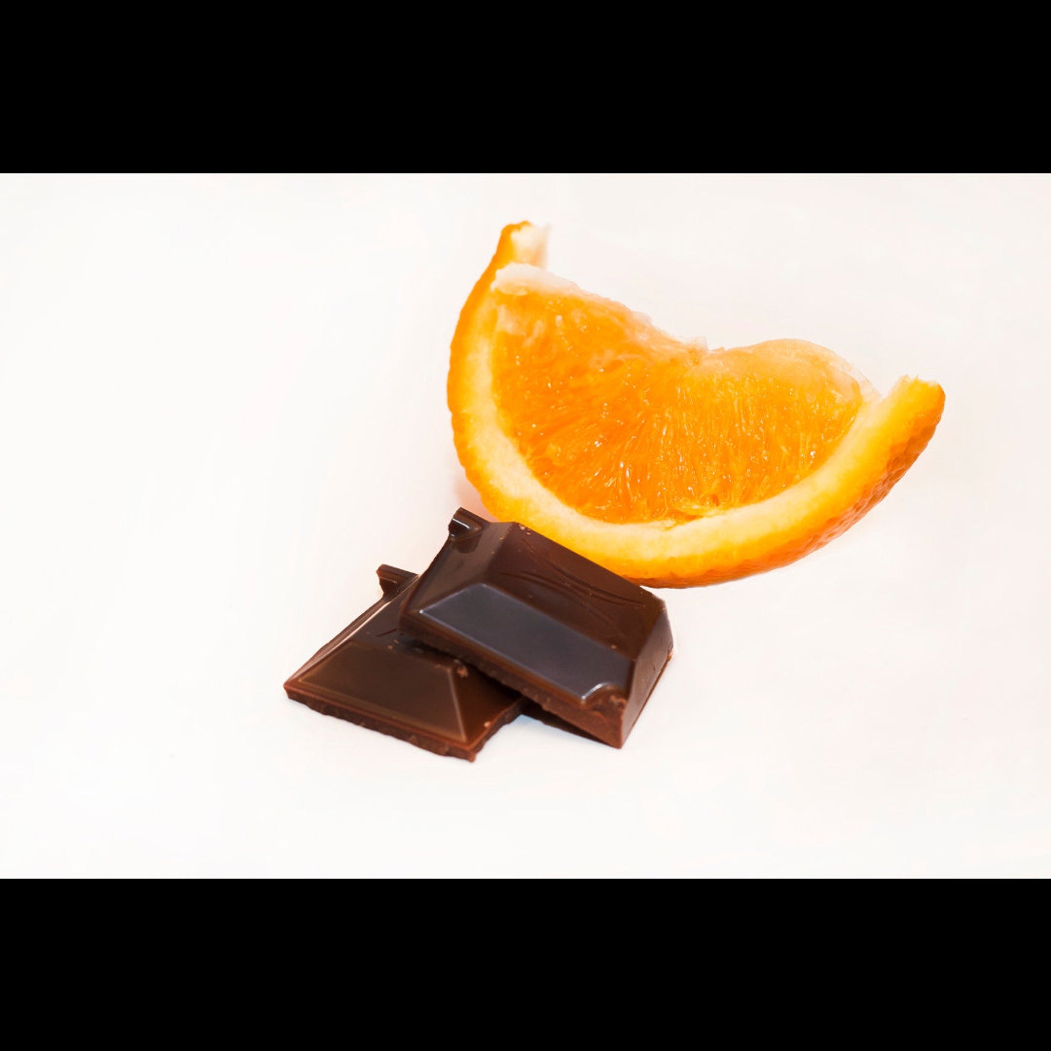 Chocolate pieces with orange slice, dark brown and orange colors on white background