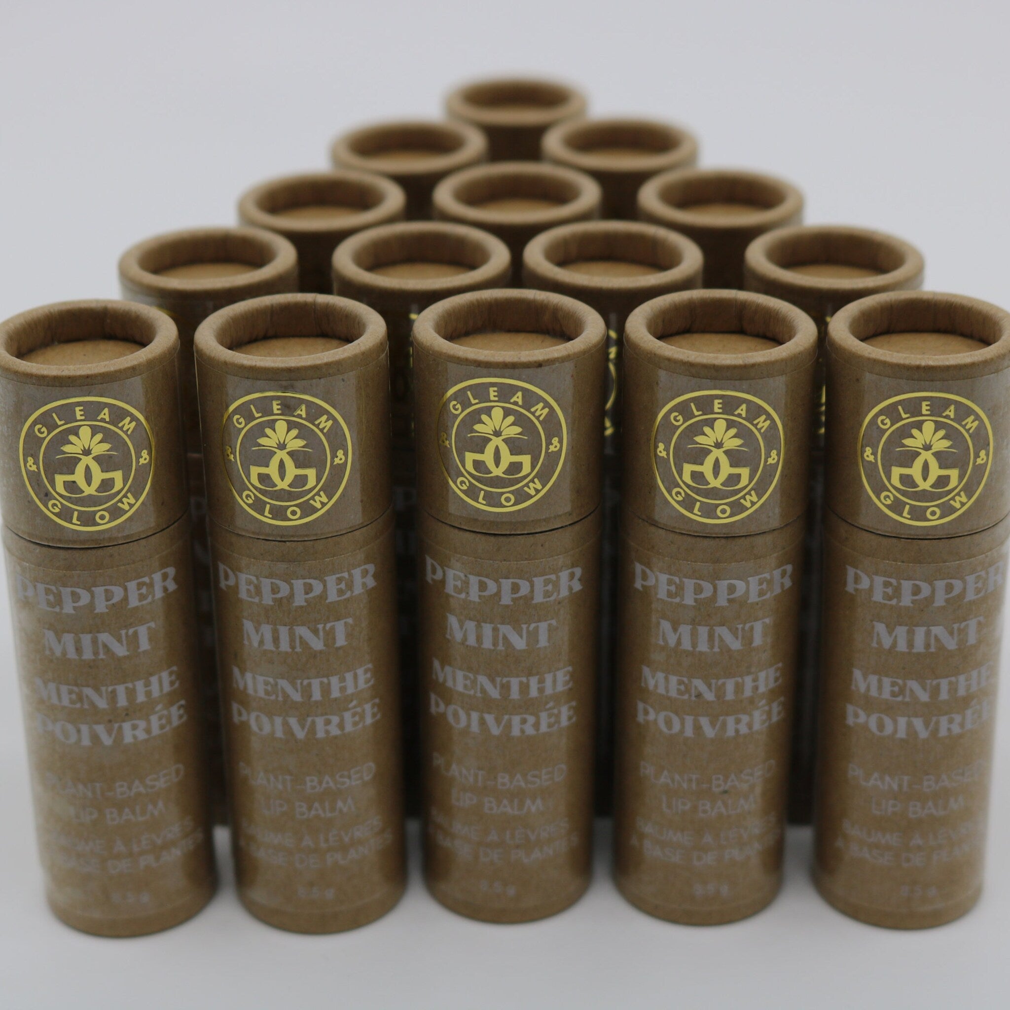 Lip balm tubes in brown cardboard with gold logo and text, arranged in a triangle formation