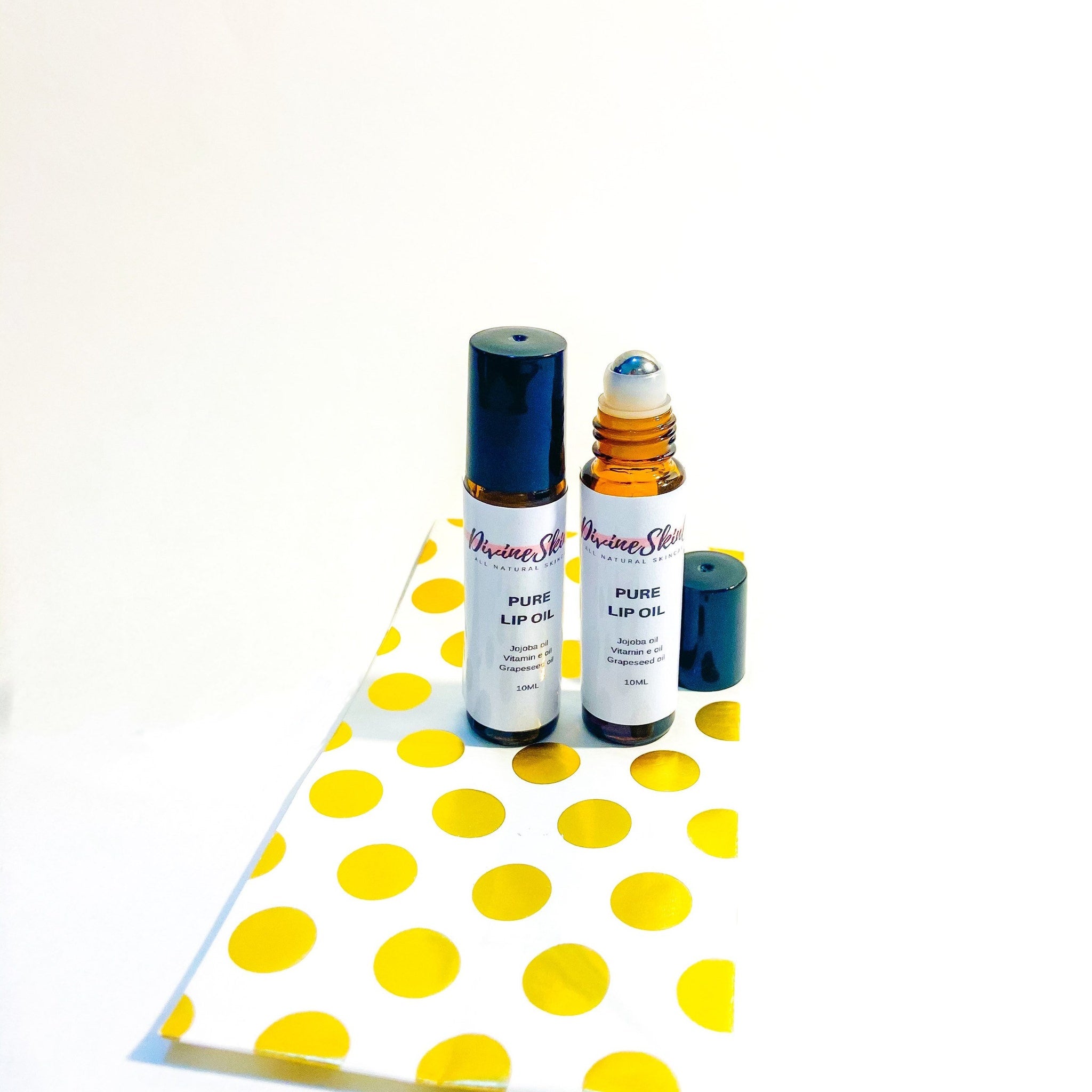 Lip oil roll-on bottles, brown glass, navy cap, Divine Skin logo visible on label