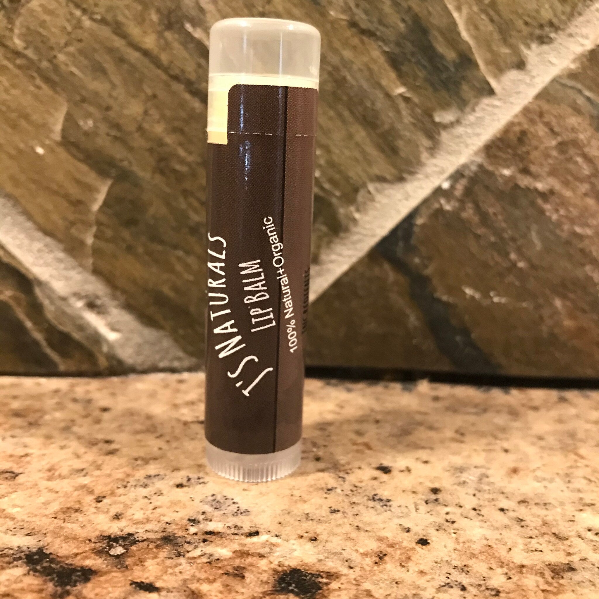 Lip balm tube with brown label, clear cap, and "S. Naturals" text visible