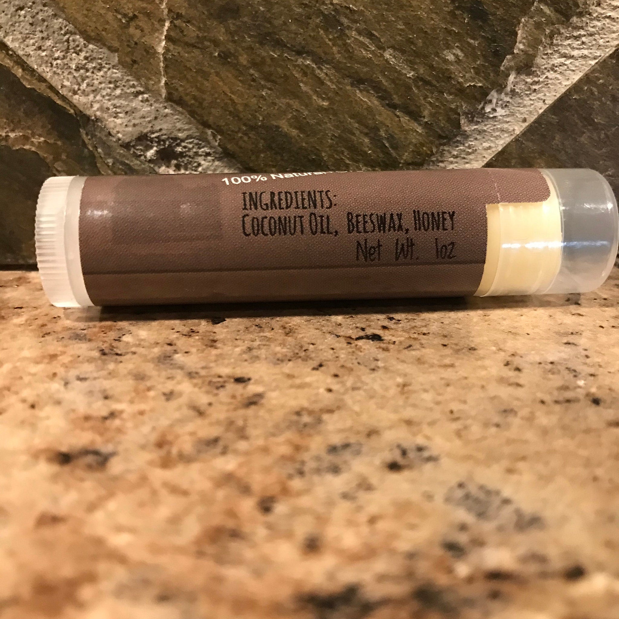 Lip balm tube with brown label, clear plastic, and white cap, ingredients visible