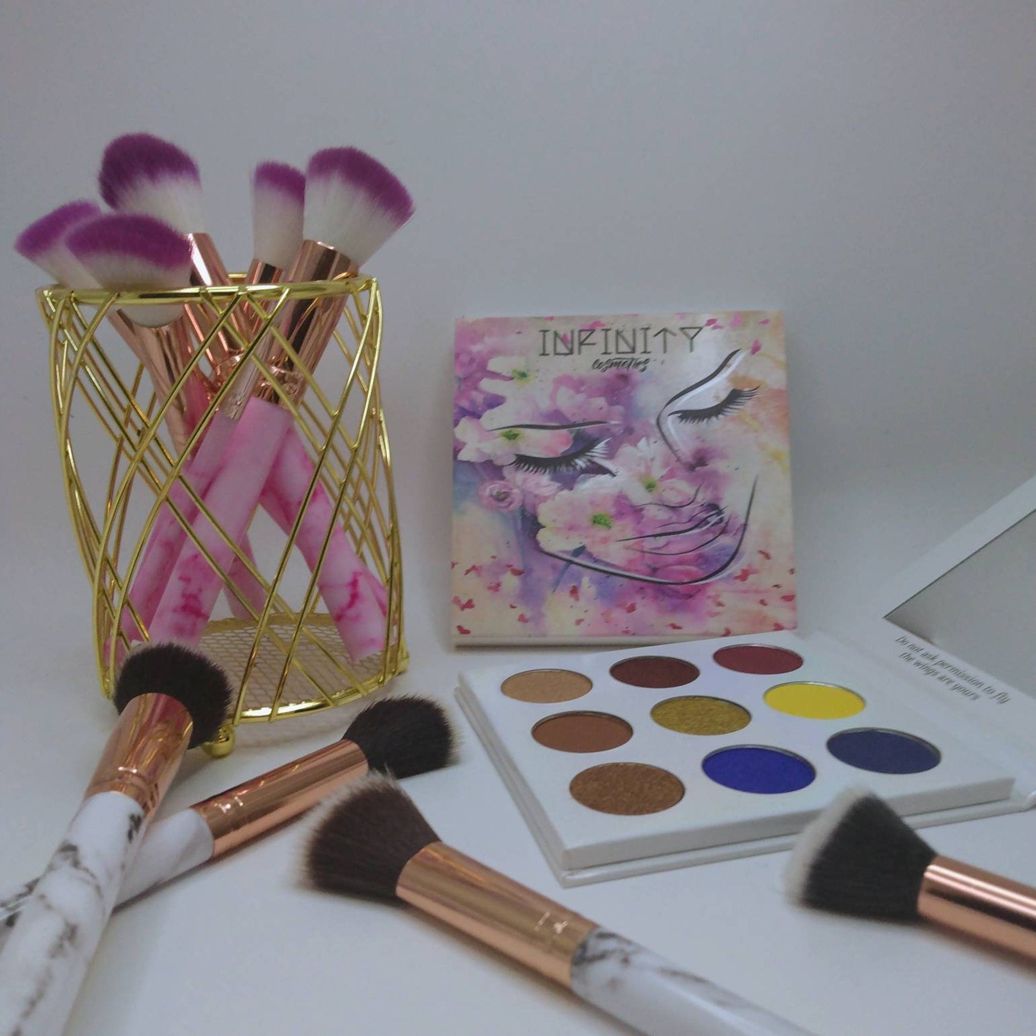 Open eye shadow palette displaying six matte and shimmer shades in neutral tones, arranged in rectangular pans with black compact.