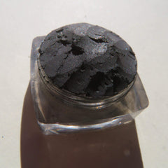 Close-up of black shimmer loose mineral eyeshadow with sparkling silver flecks in a sleek jar