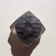 Side view of black shimmer loose mineral eyeshadow with reflective sparkles in a clear jar