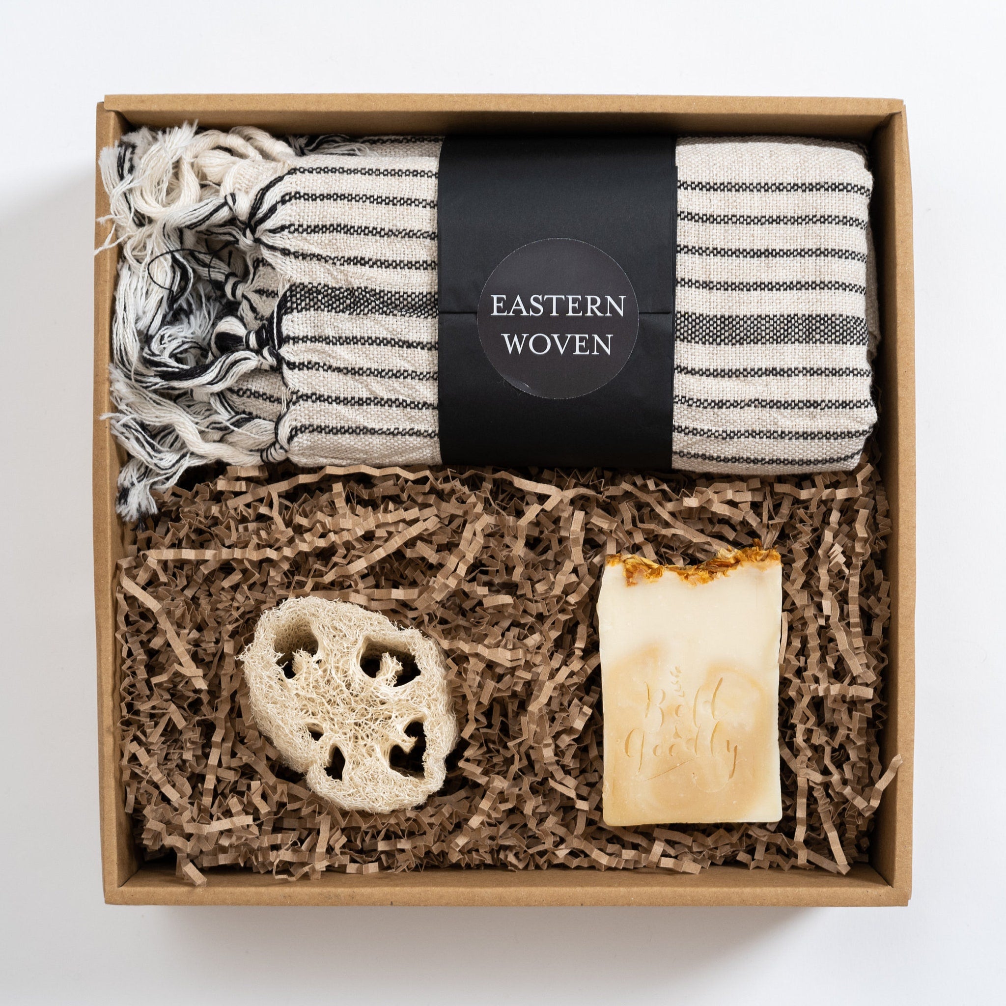 Gift box with black and white striped towel, soap, and loofah, "Eastern Woven" label visible