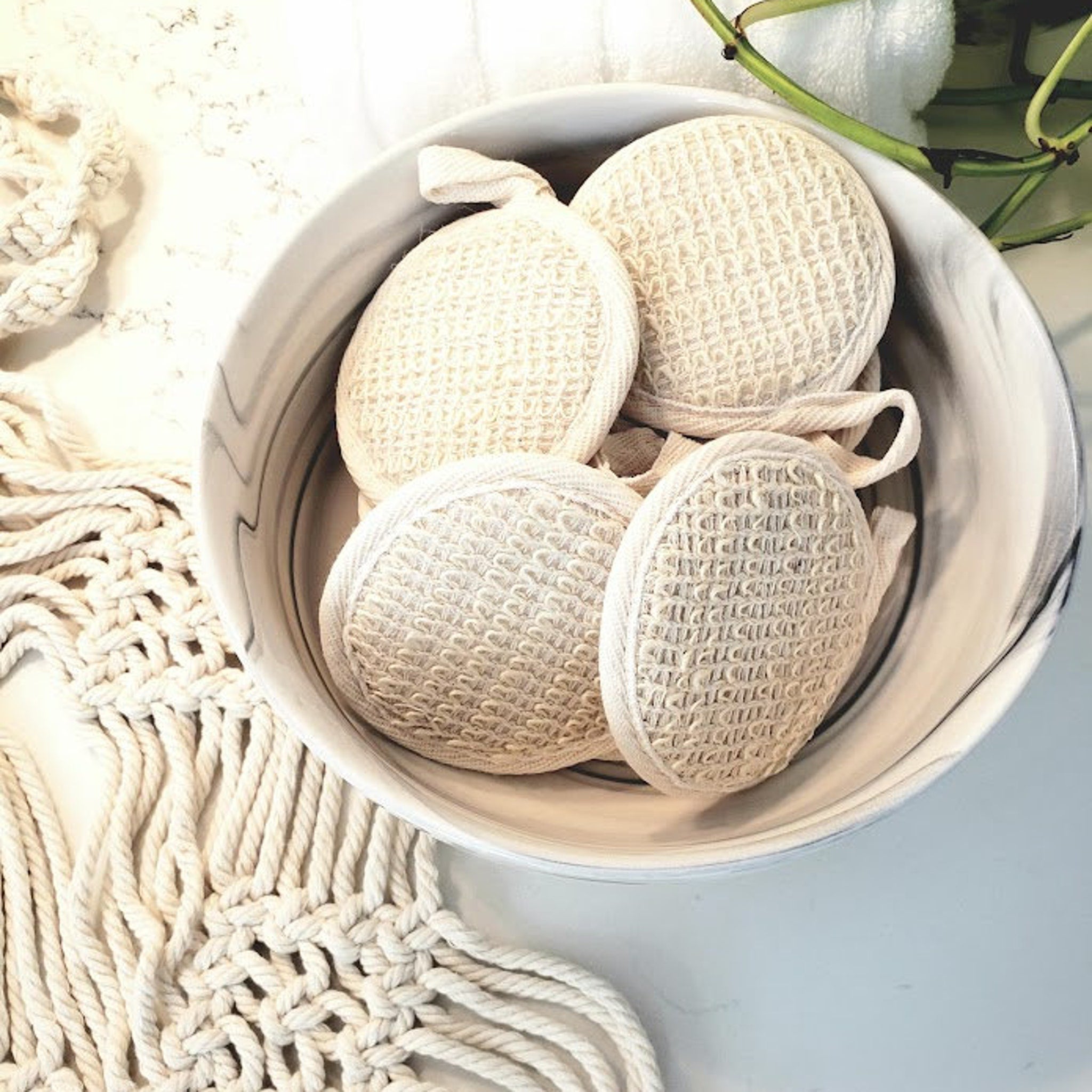 Loofah scrubbers, natural woven texture, cream color, in bowl