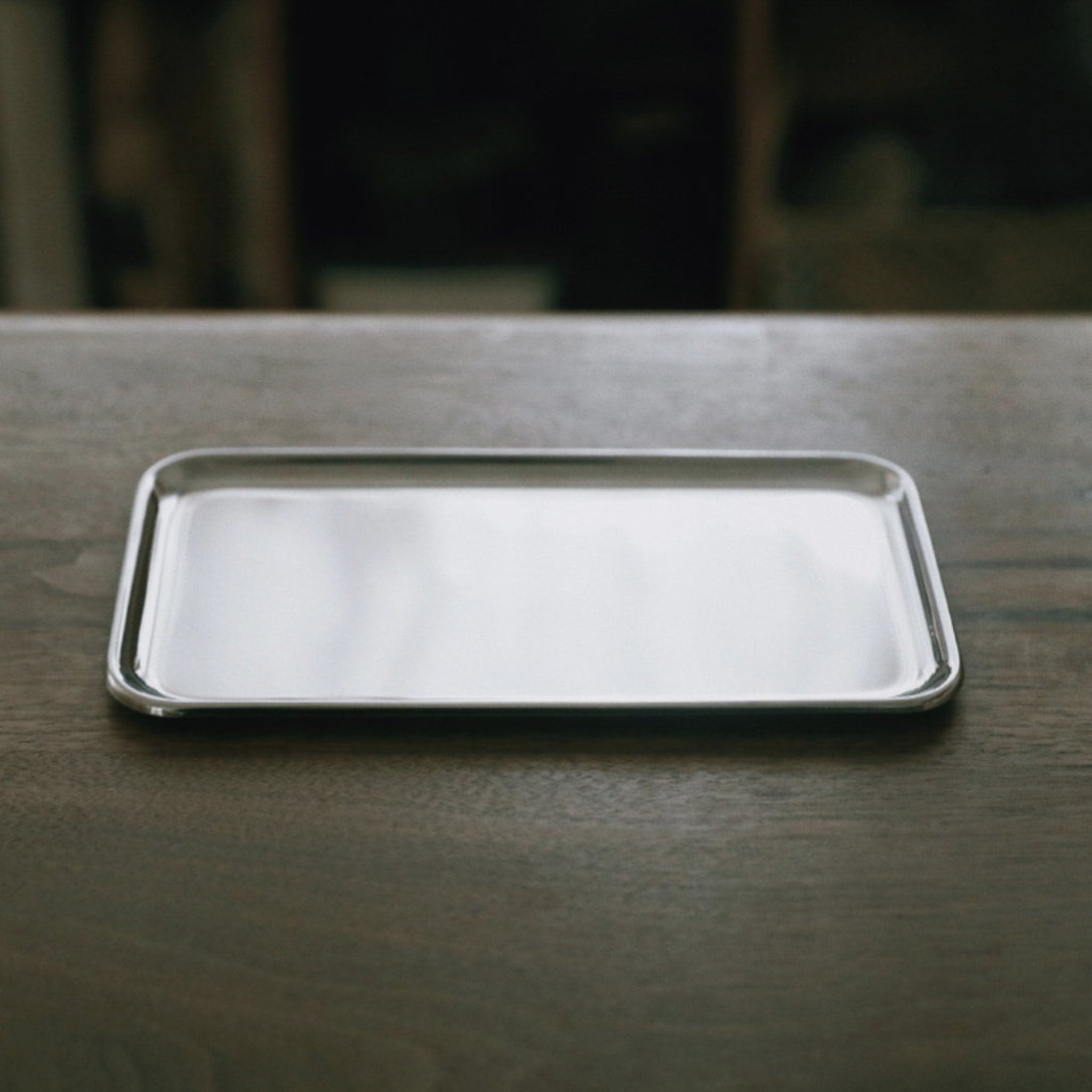 Serving tray, silver metal, rectangular shape, on a wooden surface