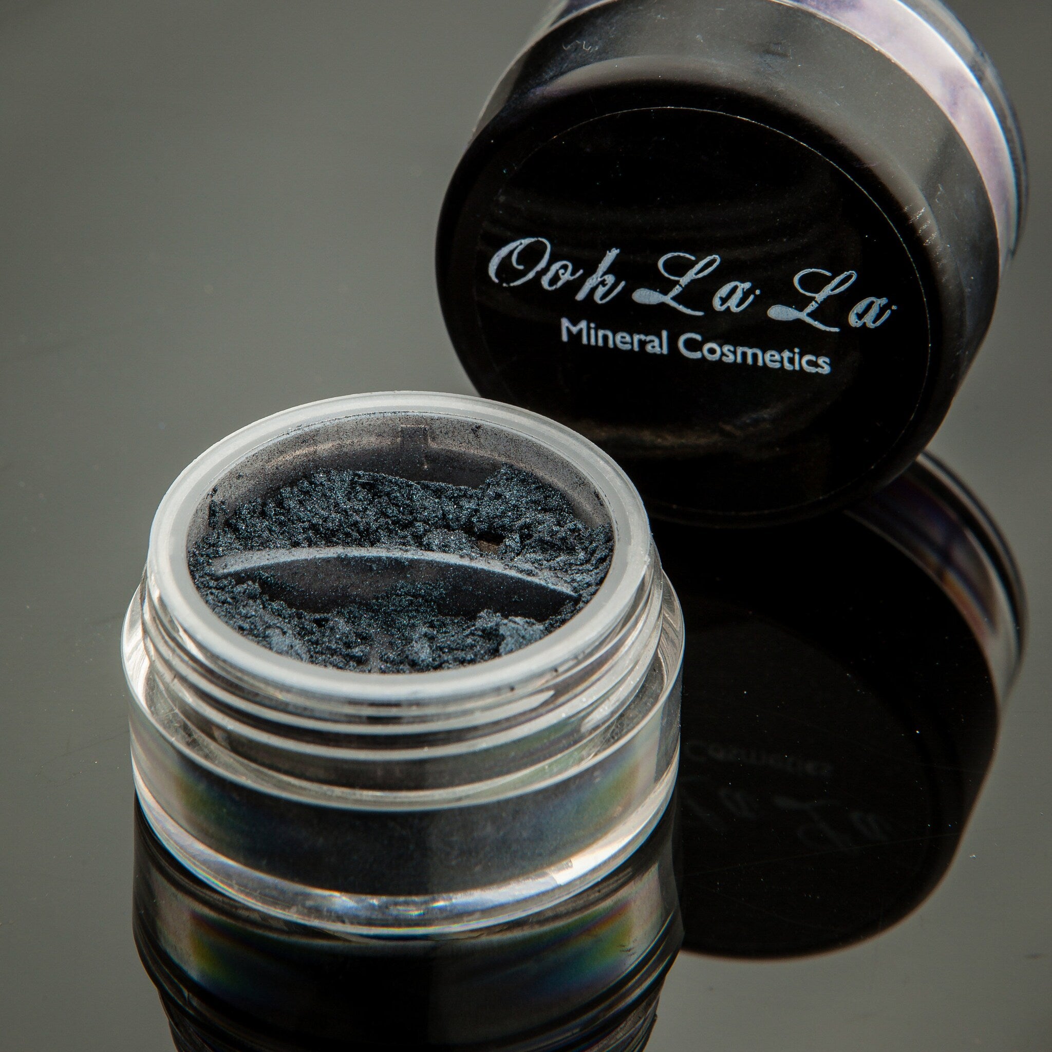 Side view of white, silver, and black mineral eye shadow in a 10g jar with matte black lid and vegan label