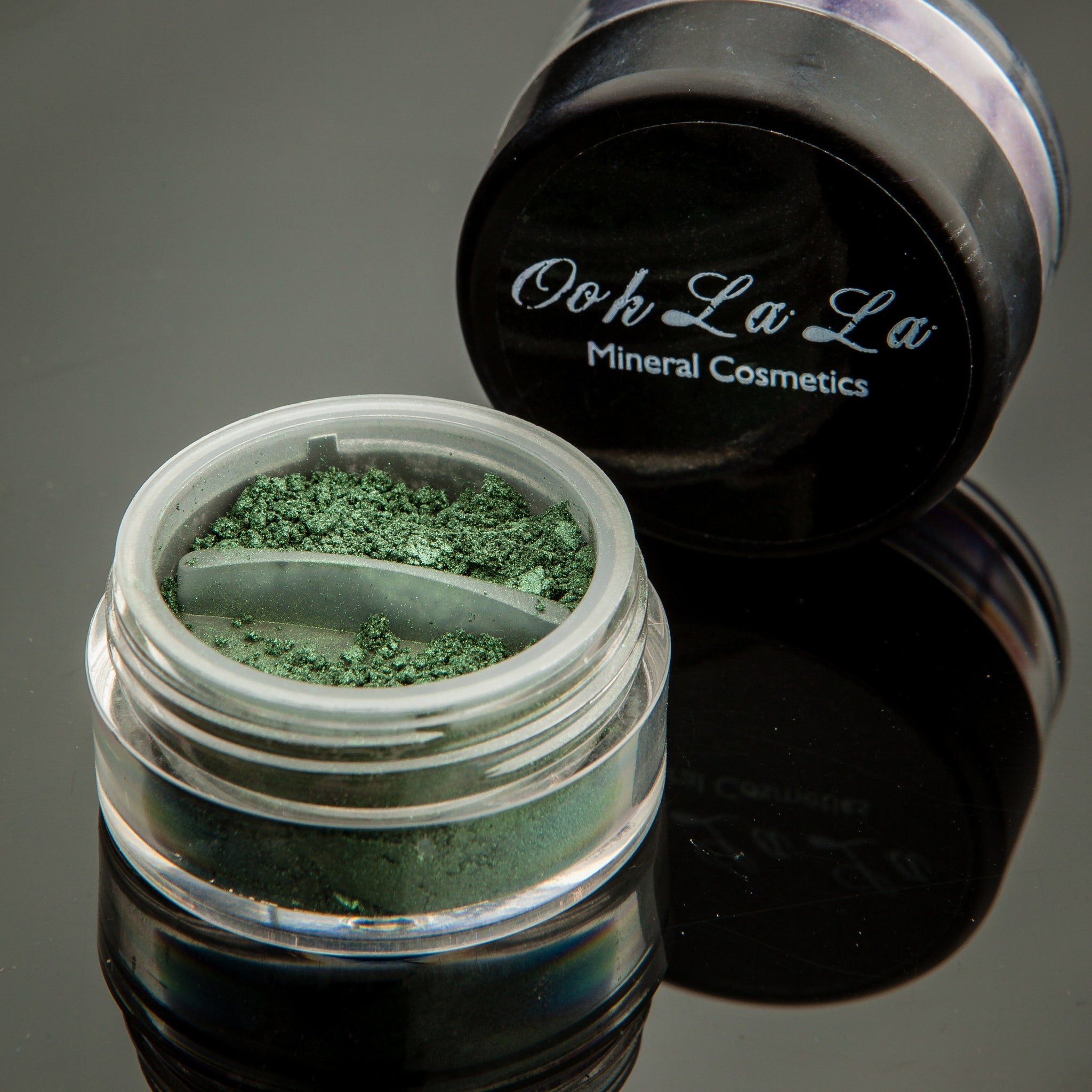 Hand applying green mineral eye shadow with a fluffy brush for a soft, blended look on the eyelid