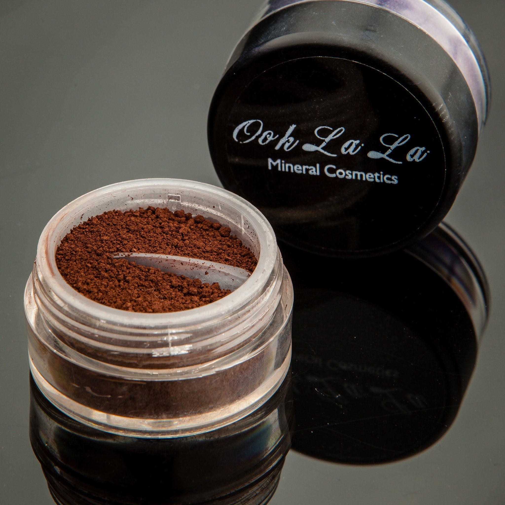 Side view of open brown mineral eyeshadow jar showing soft pressed powder texture in neutral earthy tones