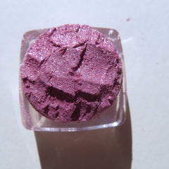 Hand applying shimmery red-pink vegan loose eye shadow pigment with a brush for a festive candy cane look