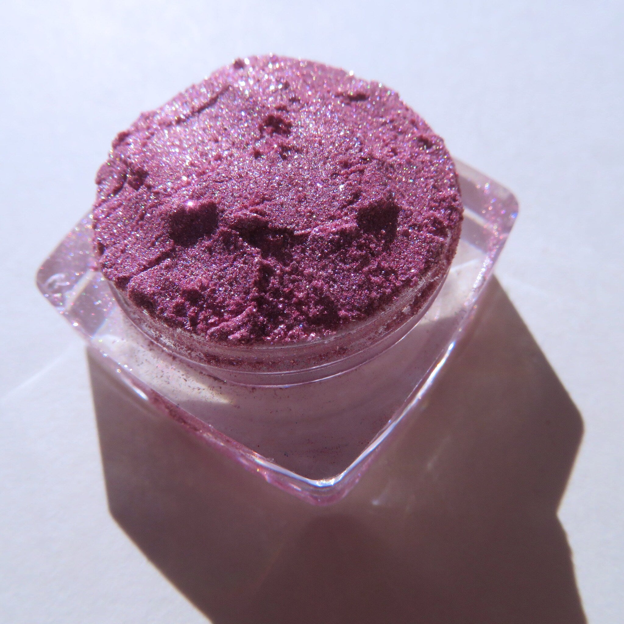 Close-up of loose shimmery red pink vegan eye shadow pigment with sparkling candy cane flecks