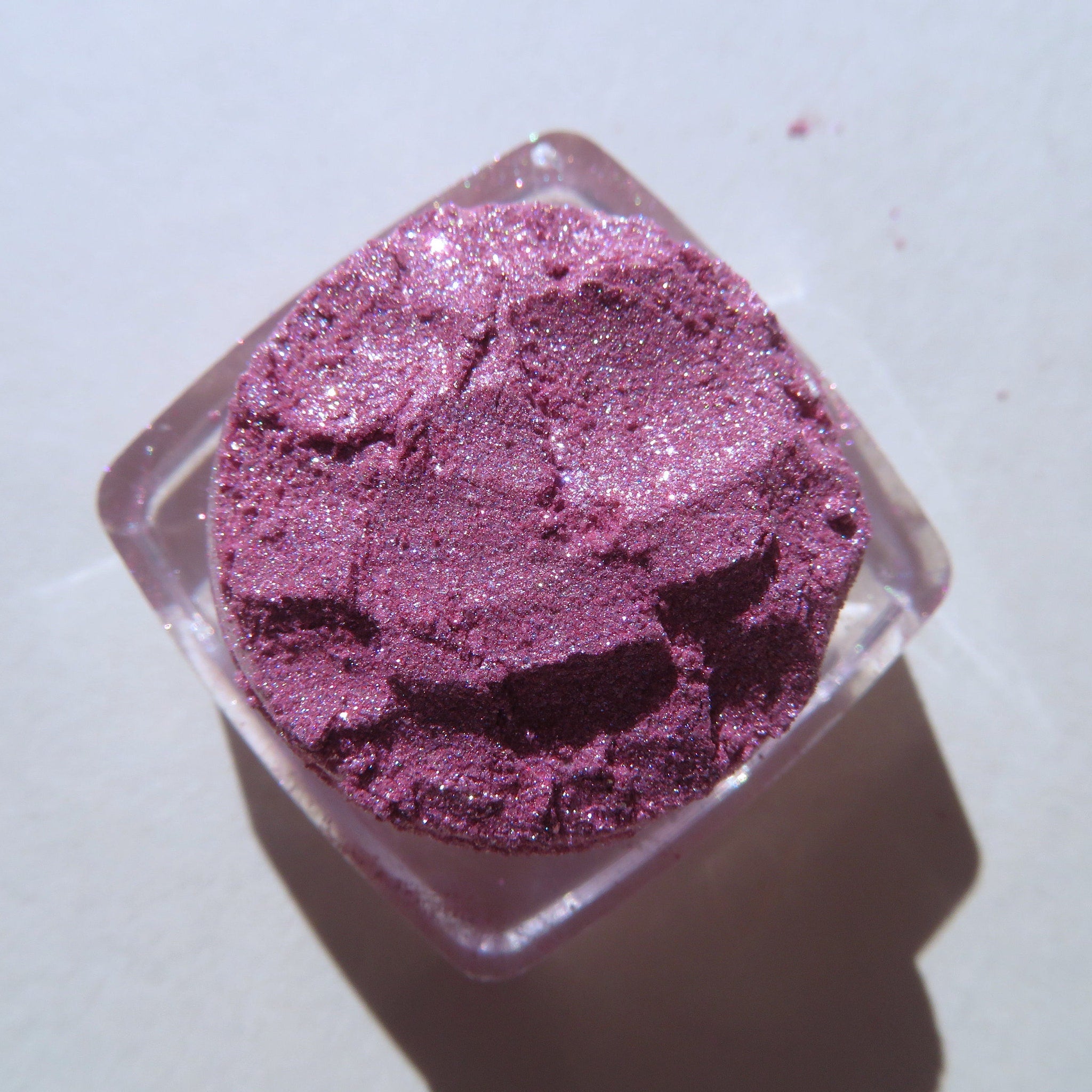 Close-up of loose shimmery red-pink vegan eye shadow powder with sparkling candy cane flecks
