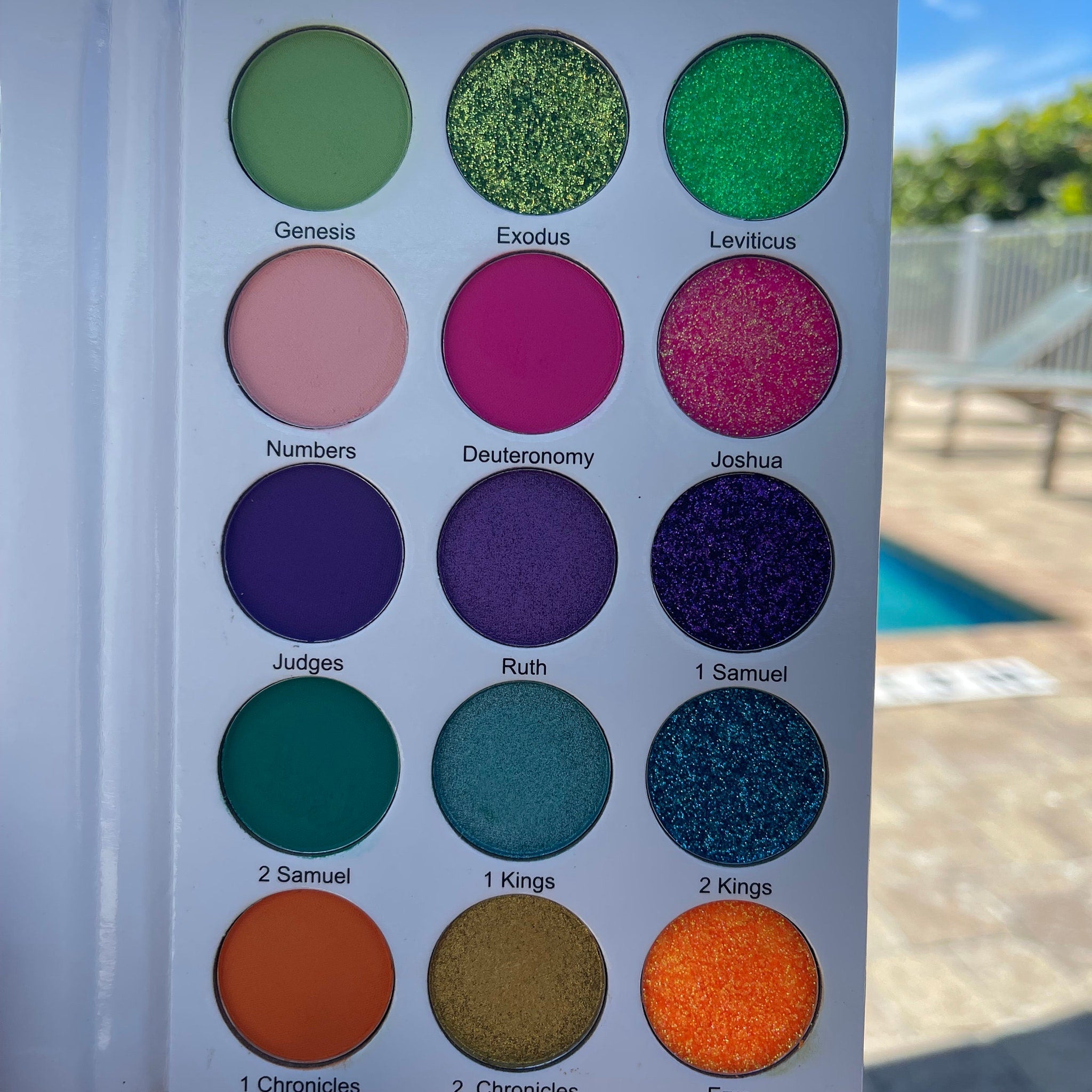 Eyeshadow palette with various colors, including green, pink, purple, and orange, in a circular pan style