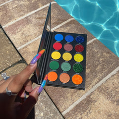 Eyeshadow palette with colorful eyeshadows, black case, held by hand near pool