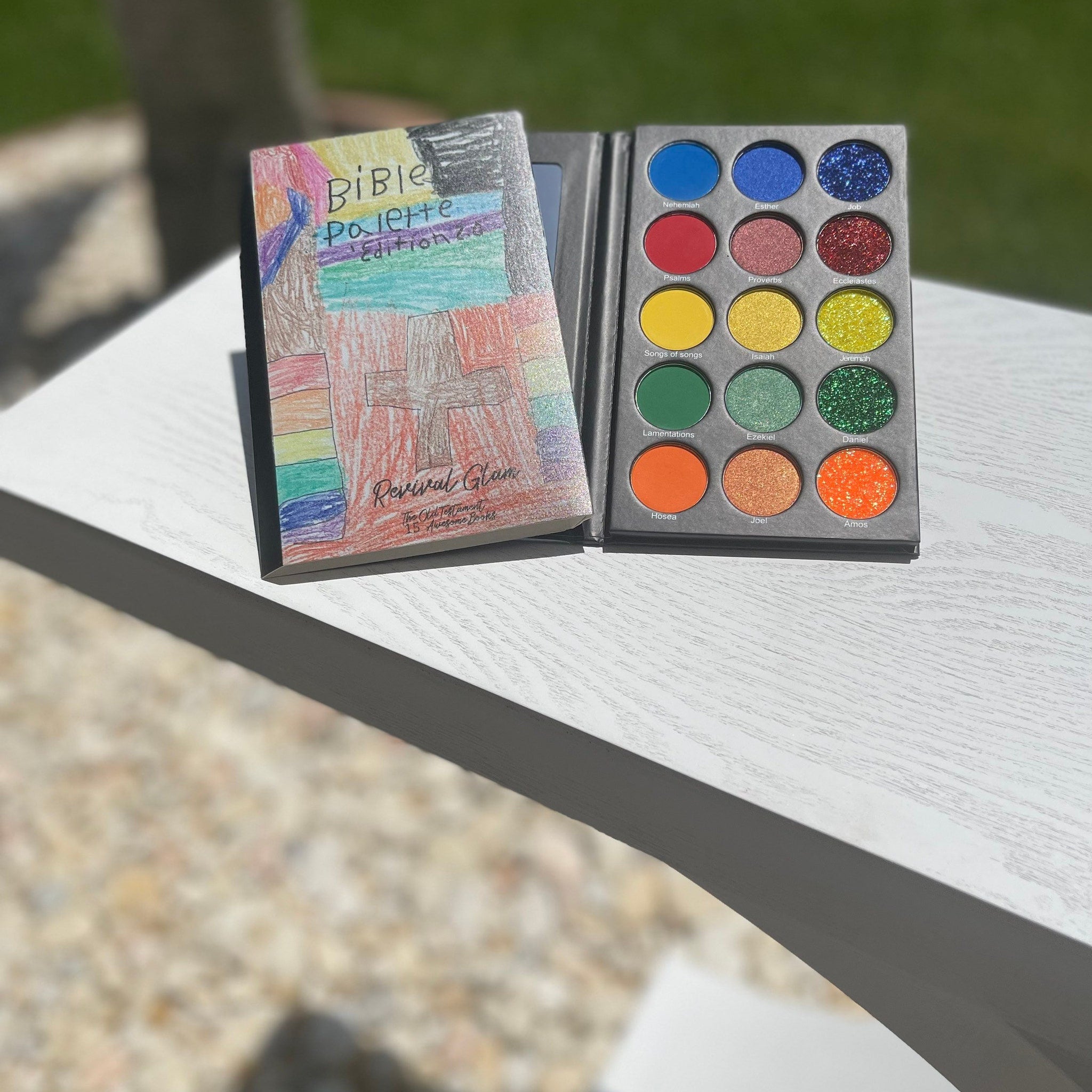 Eyeshadow palette with colorful shades and Revival Glam branding on a book-style cover