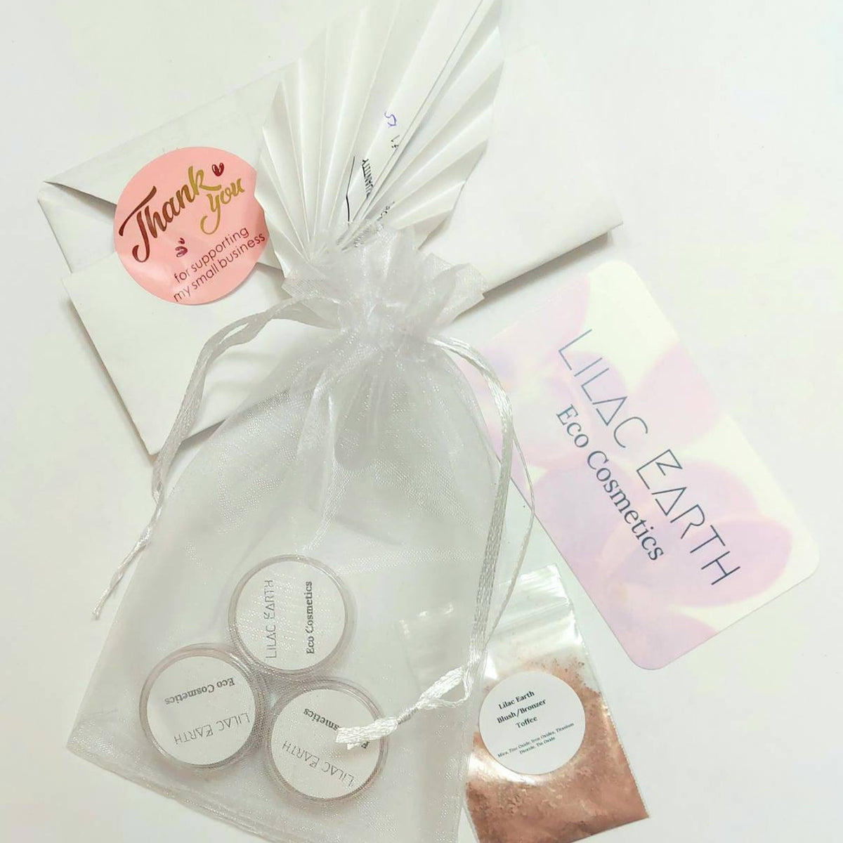 Three small glass jars of vegan mineral eyeshadow in natural shades with matte and shimmer finishes