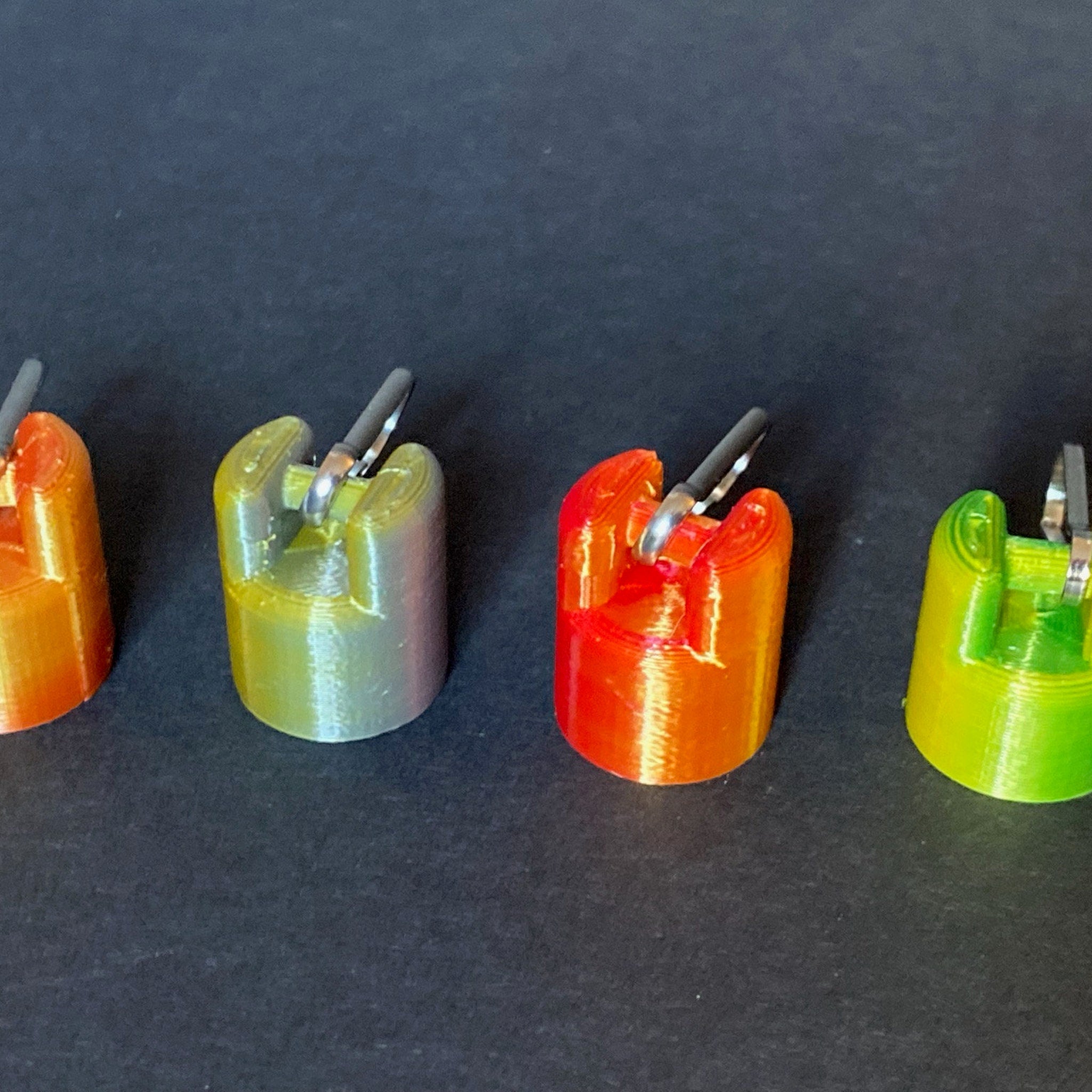 Colorful 3D printed objects with metal rings, various colors, cylindrical shape