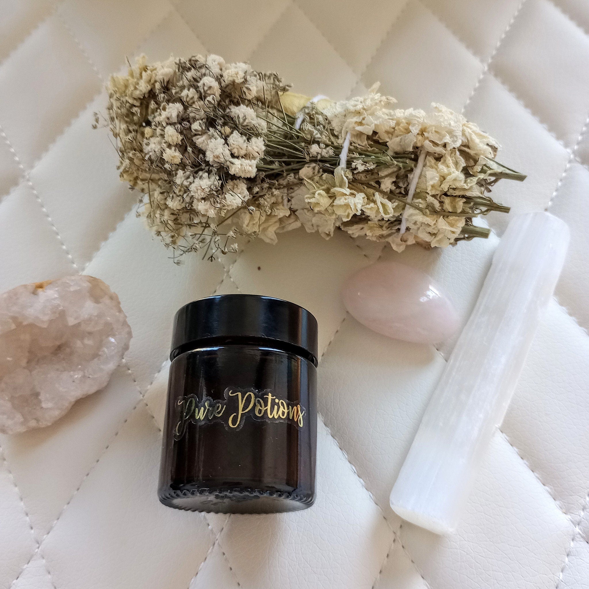 Pure Potions jar, brown glass, gold script label, with crystals and dried flowers on white quilted surface