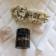 Pure Potions jar, brown glass, gold script label, with crystals and dried flowers on white quilted surface