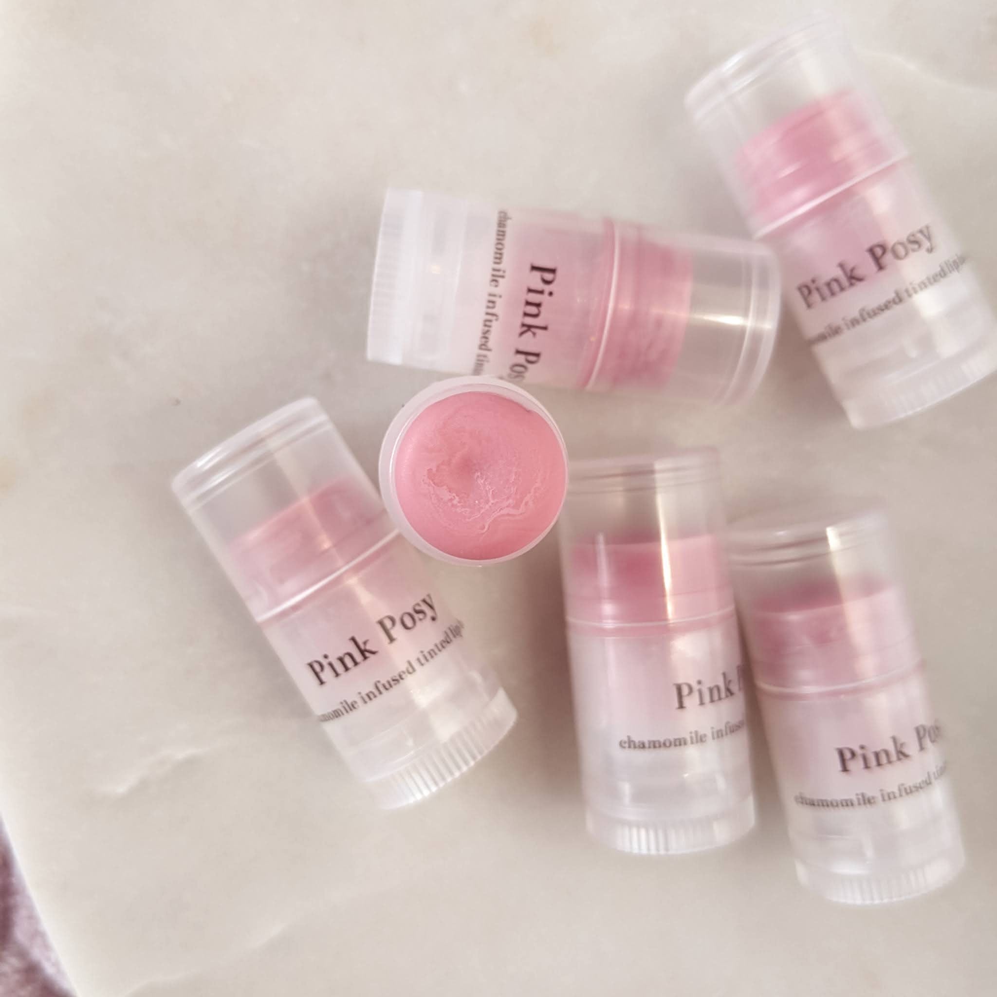 Lip balm tubes with pink color, clear plastic, and "Pink Posy" text visible on the label