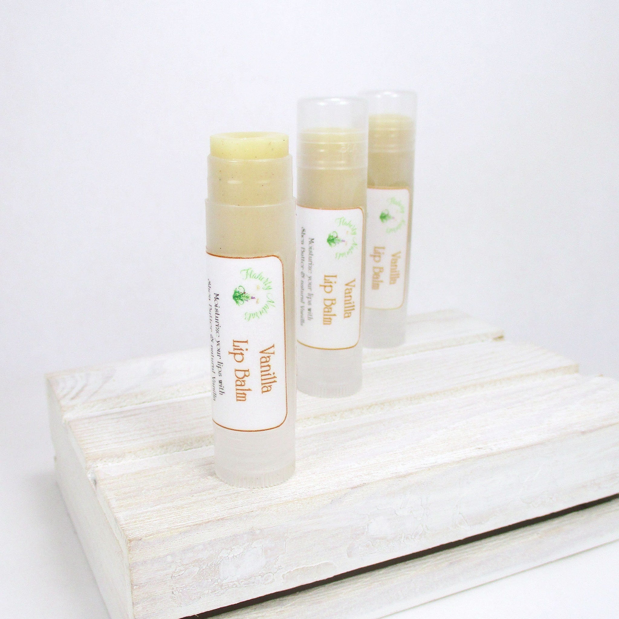 Lip balm tubes with beige balm, clear plastic casing, and Flaherty Naturals labels on a white wooden surface