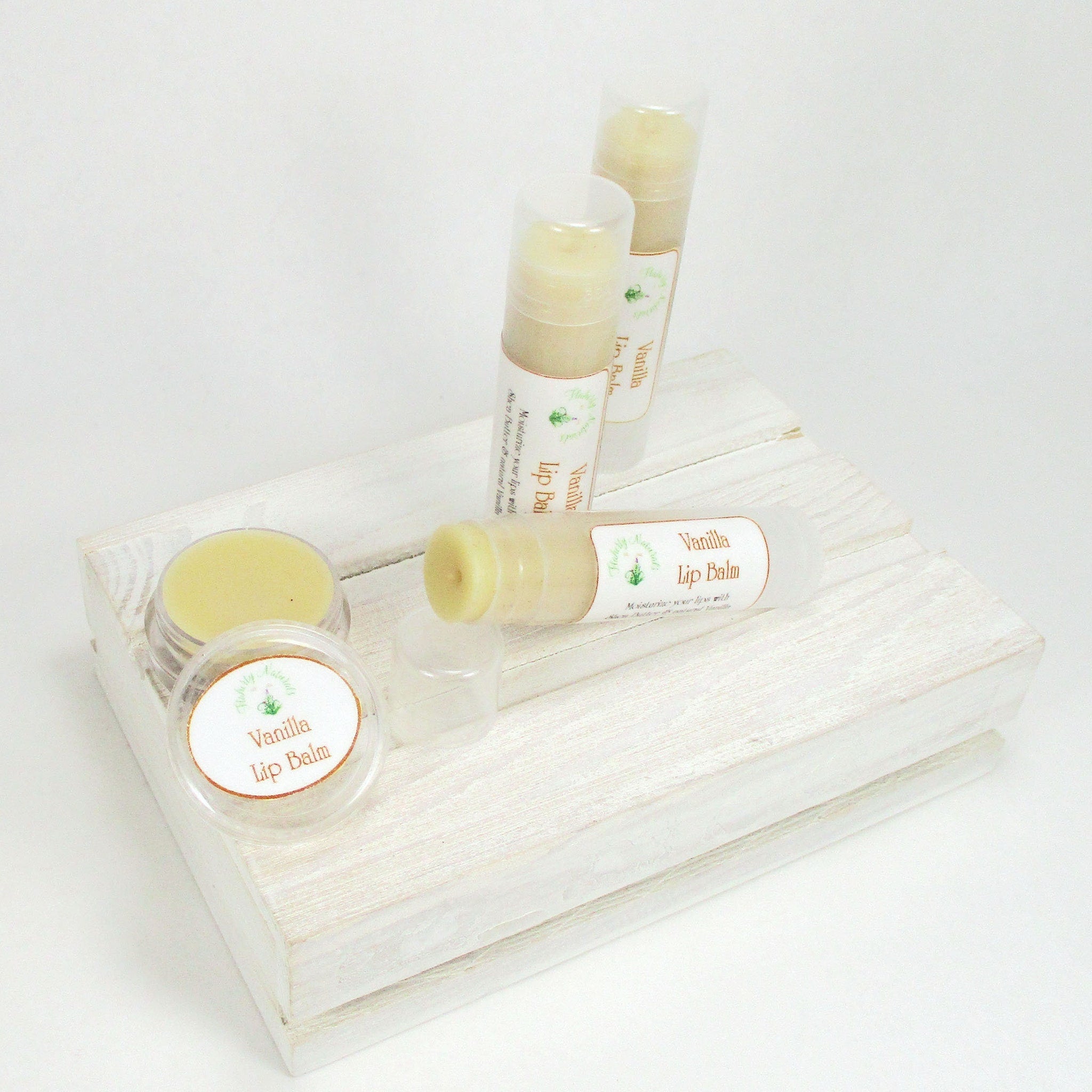Lip balm tubes and jar with light yellow balm, white labels, and wooden display