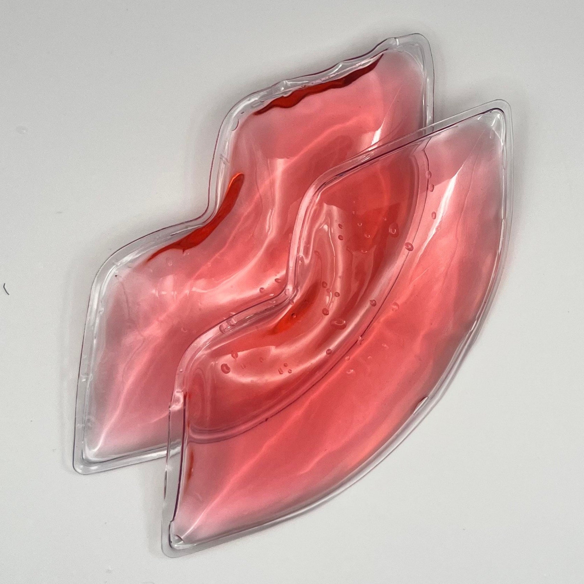 Lip ice packs, red gel-filled, clear plastic lip-shaped, on white background