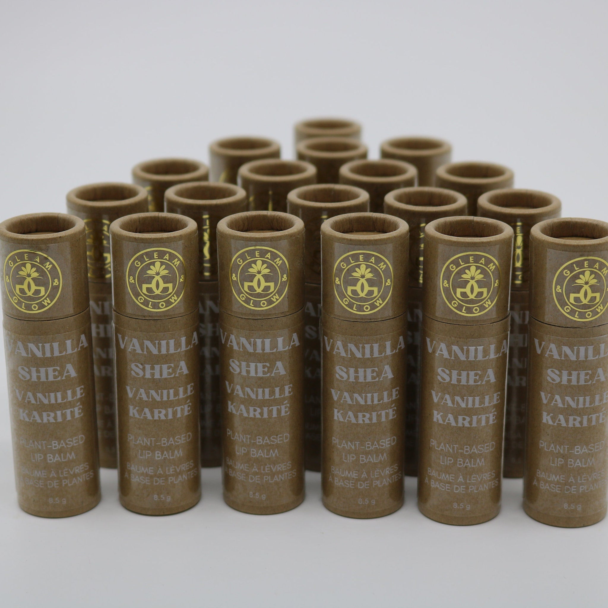 Lip balm tubes in brown paper packaging with gold text, "GLEAM & GLOW" brand name visible