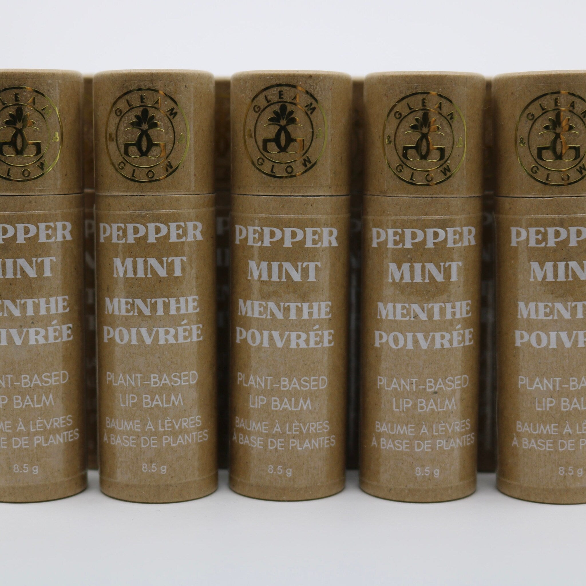 Plant-based lip balm tubes in brown cardboard with gold logo and white text, GLEAM & GLOW brand