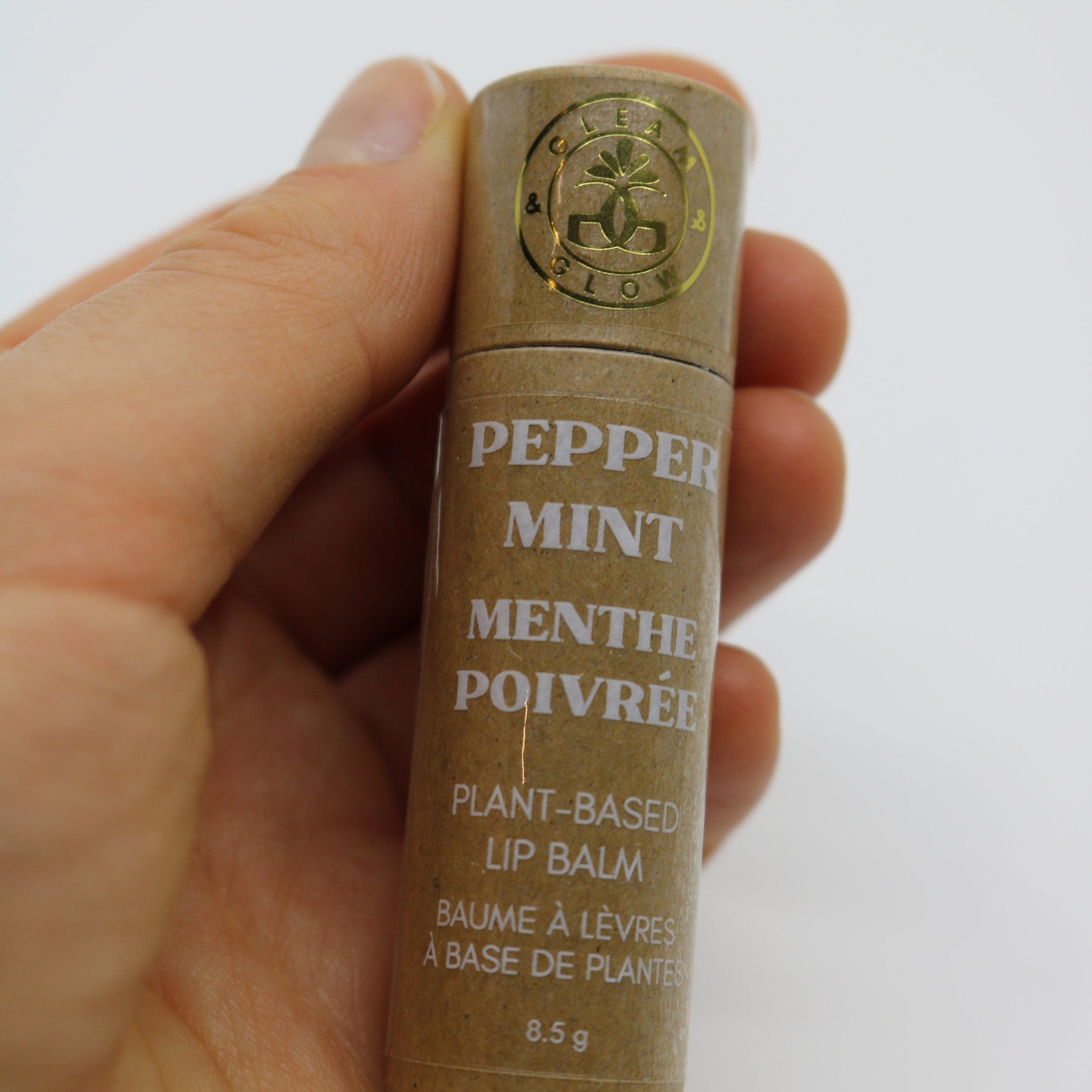 Peppermint lip balm in brown paper tube with white text, held in hand, GLEAM & GLOW brand visible