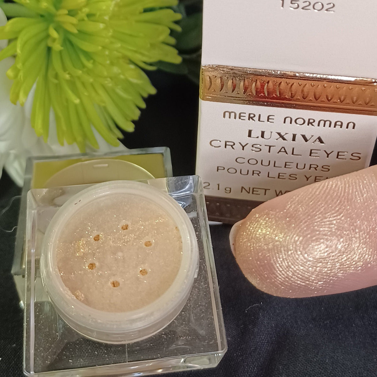 Merle Norman loose glitter eyeshadow in a small jar with shimmering powder particles catching light