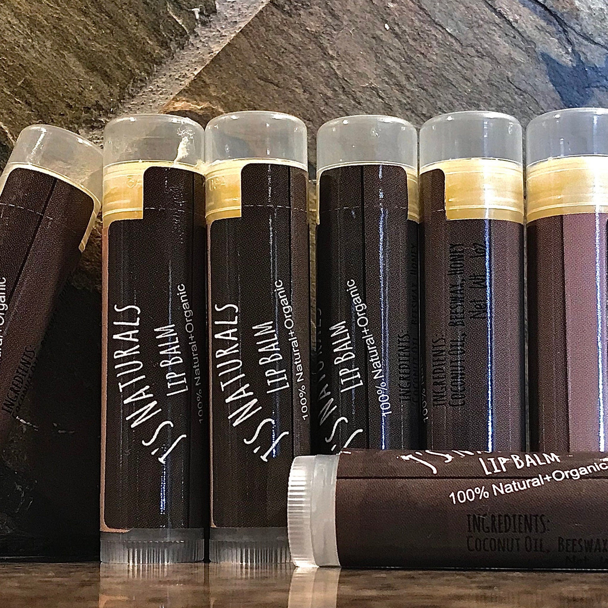 Lip balm tubes with brown textured paper, gold band, and clear caps, J's Naturals branding visible