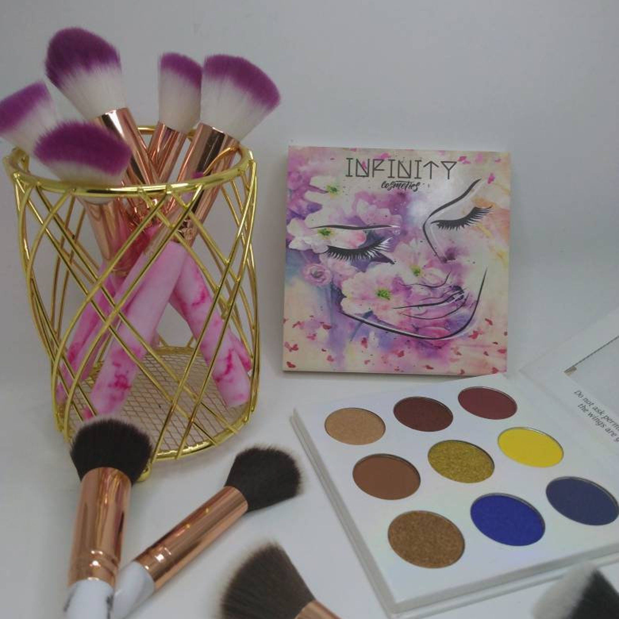 Close-up of fingertips applying shimmery bronze eye shadow to eyelid with soft blending brush