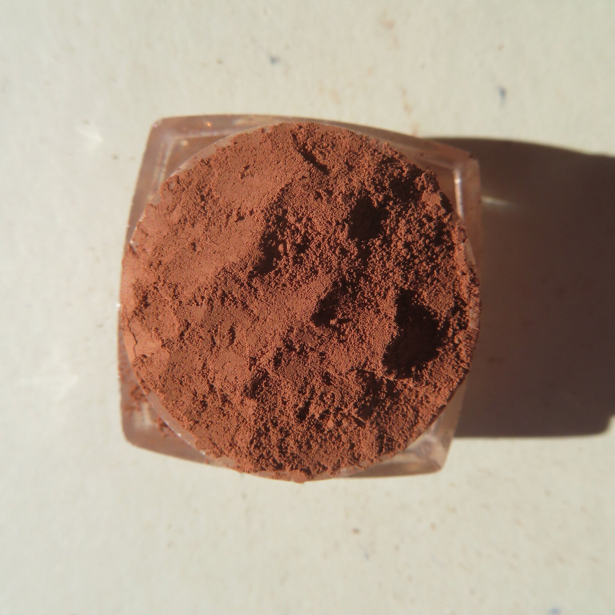 Hand applying matte medium orange-brown mineral eye shadow with a fluffy brush for a soft blended look