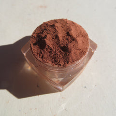 Close-up of matte medium orange-brown loose mineral eye shadow with fine mica texture in vegan, cruelty-free packaging