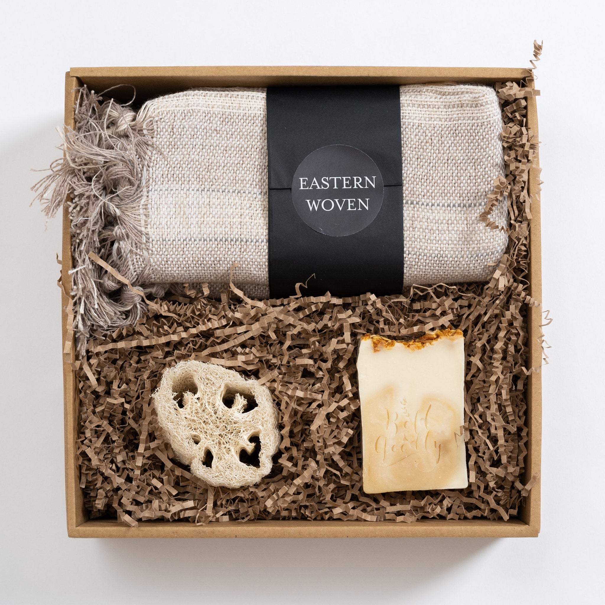 Gift box with woven beige towel, soap, and loofah in a brown box labeled Eastern Woven