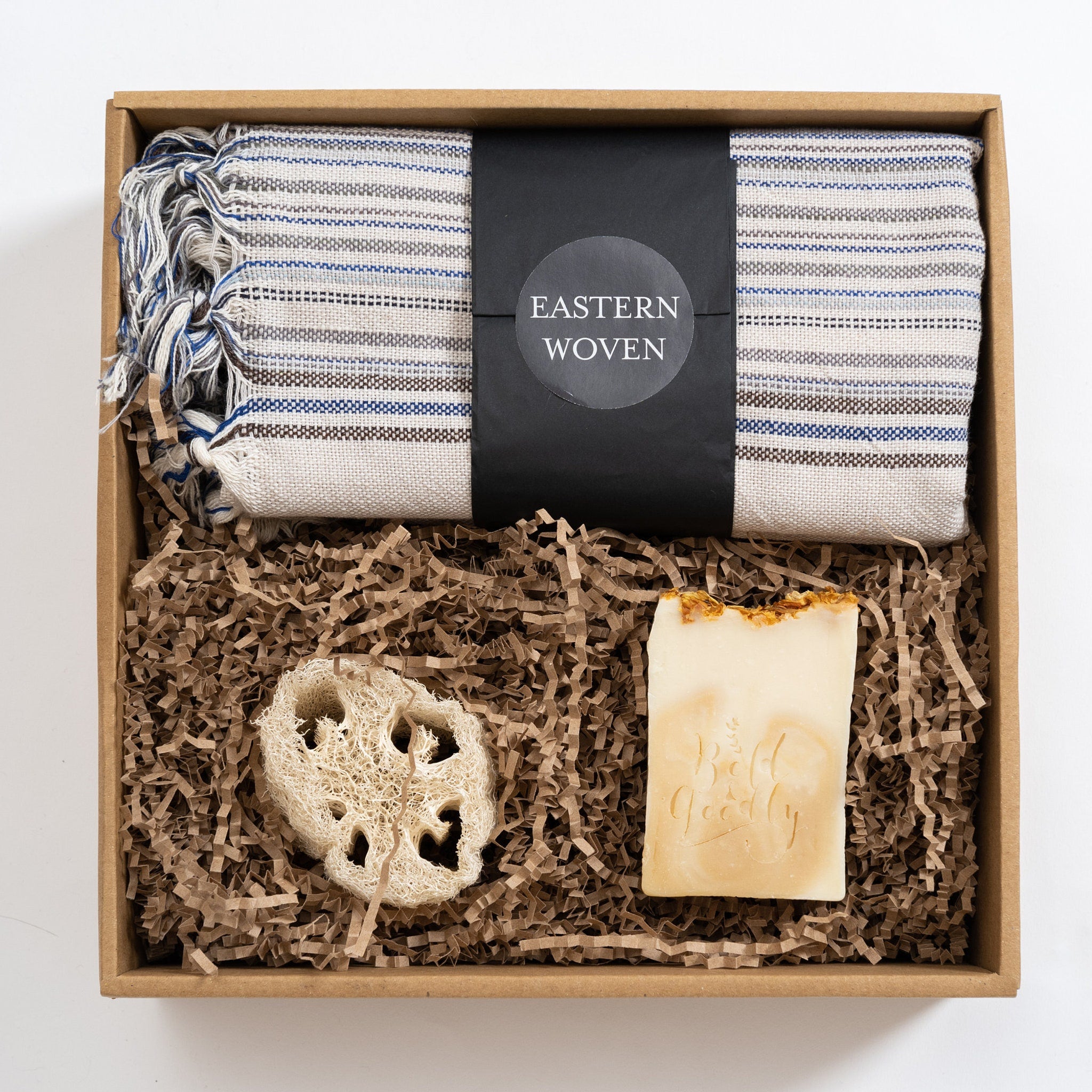 Gift box set with striped towel, loofah, and soap, with "Eastern Woven" label visible