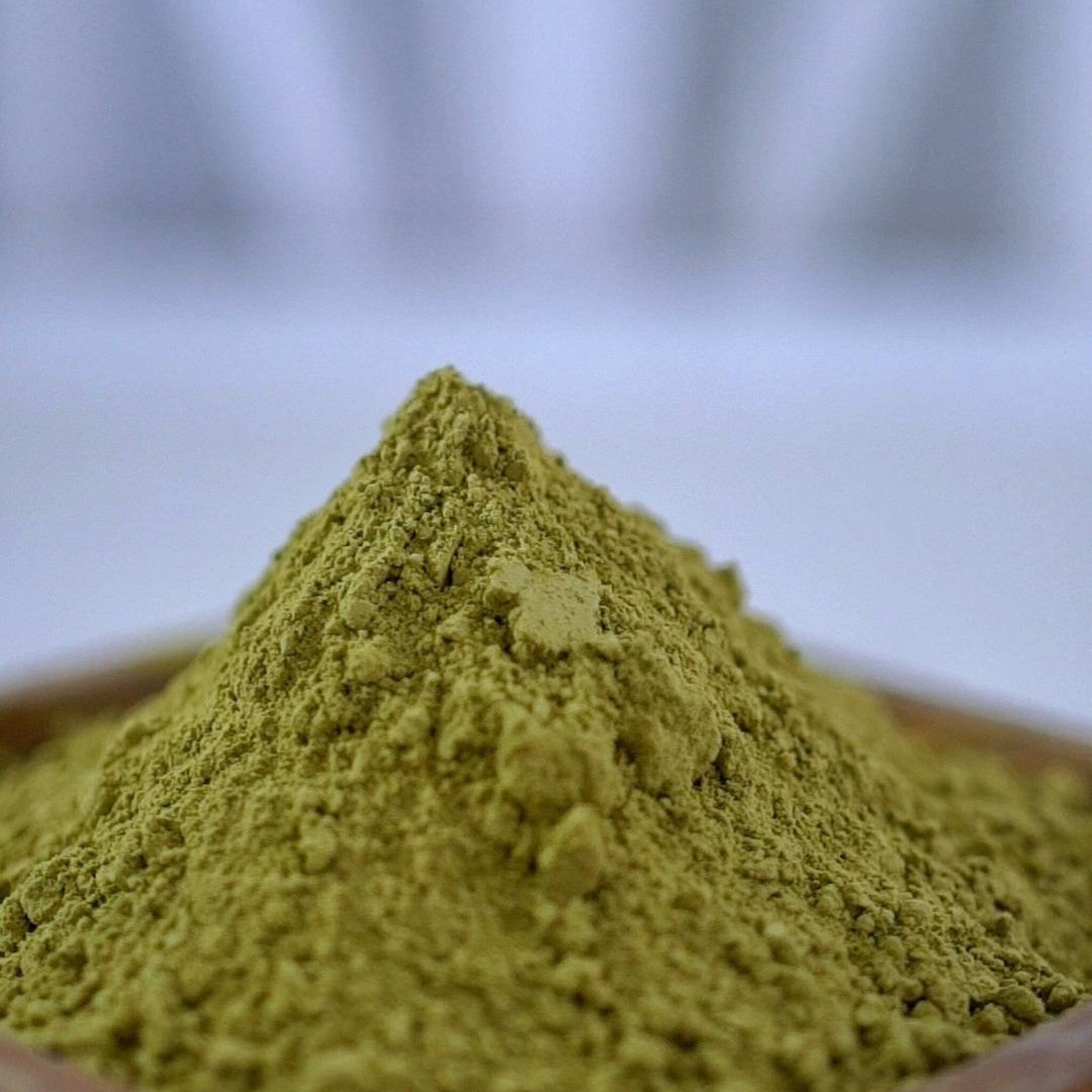 Green powder pile, fine texture, close-up view, in a wooden bowl
