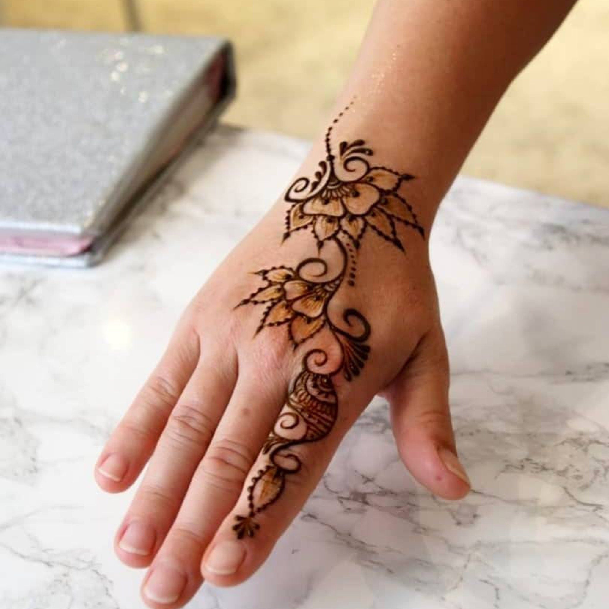 Henna tattoo design on hand with floral pattern and brown color