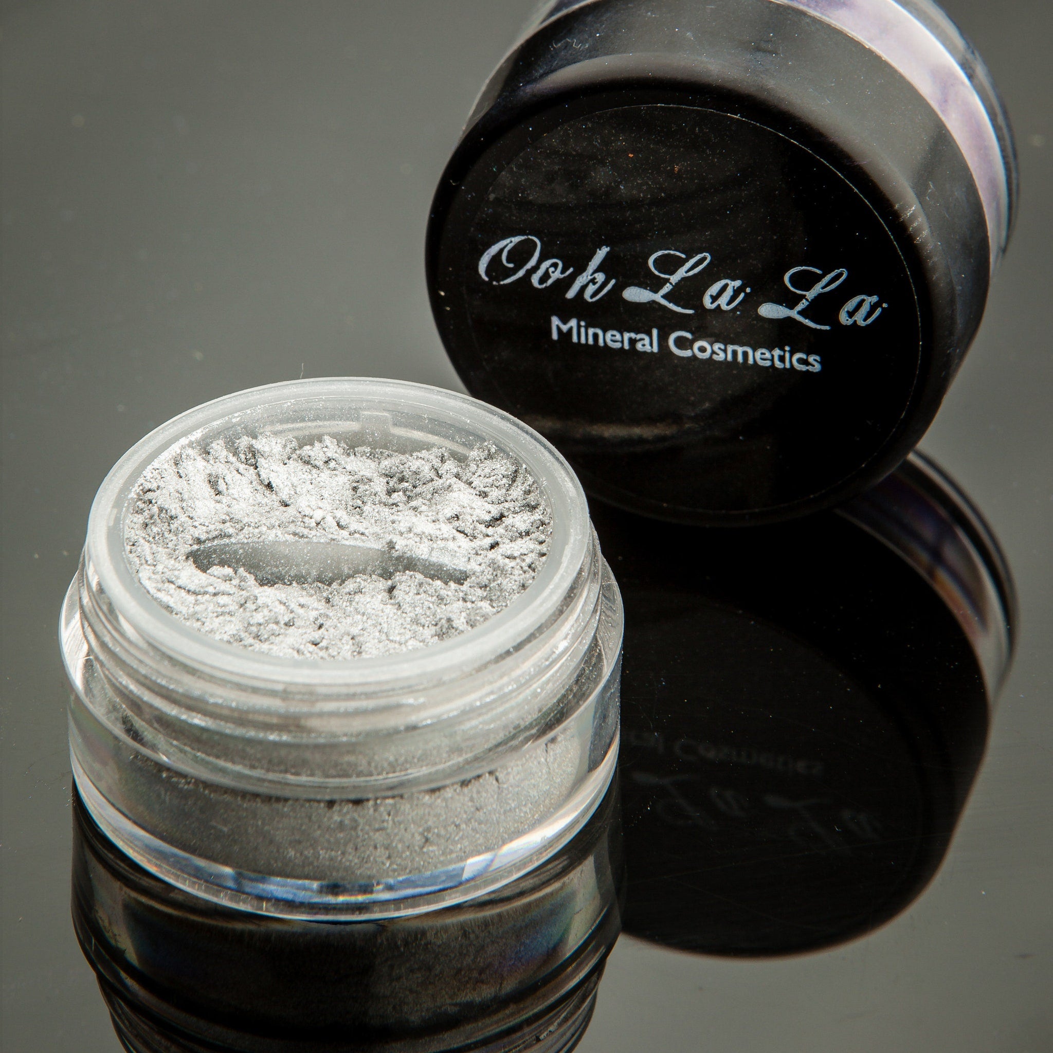 Hand applying shimmering white vegan mineral eye shadow with fingertip for a natural makeup look