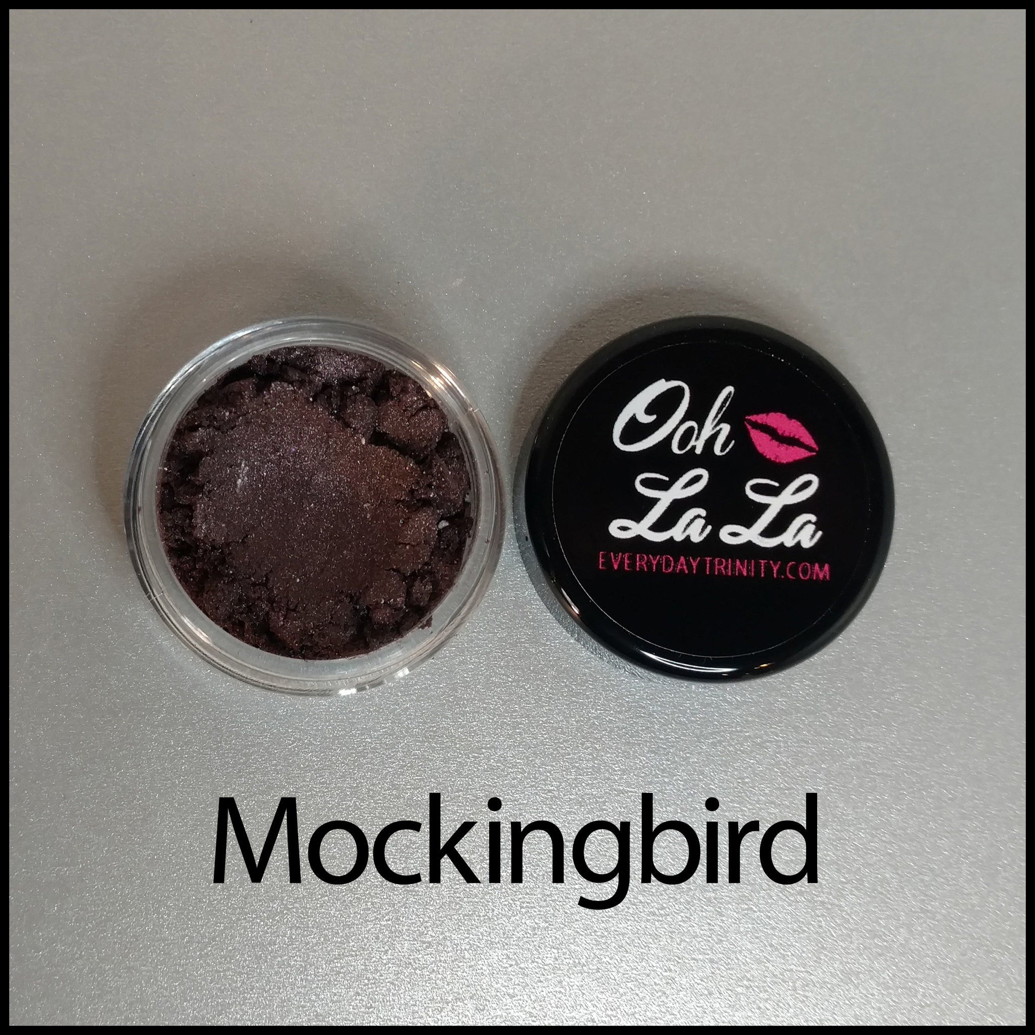 Open jar of vegan mineral eye shadow showcasing rich brown and neutral shades with smooth powder texture