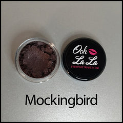 Open jar of vegan mineral eye shadow showcasing rich brown and neutral shades with smooth powder texture