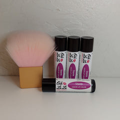 Lip color tubes with black caps, white labels, and "Ooh La La" brand text, and a pink makeup brush